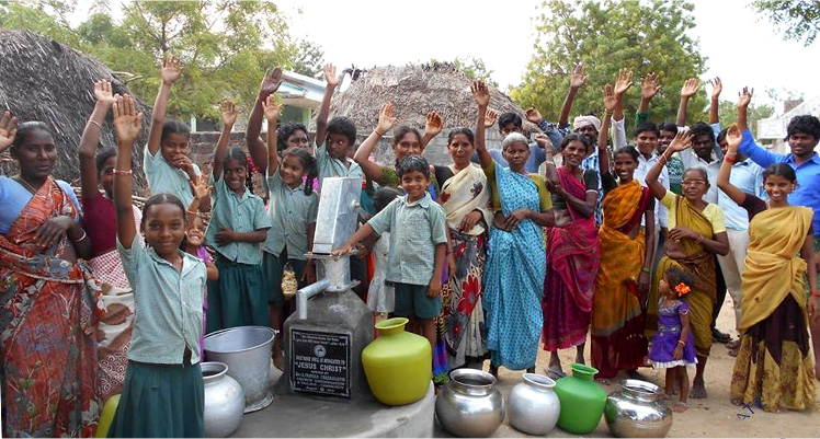 Indian village with hands raised by a new well